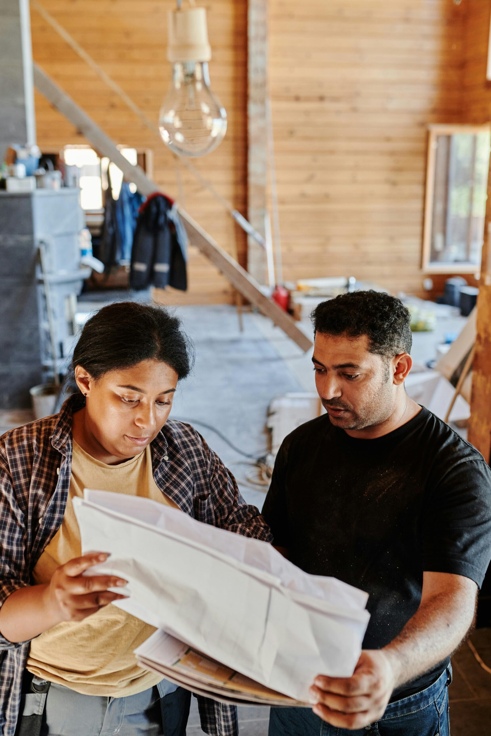 Two professionals reviewing construction plans indoors during the day.